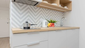 A modern kitchen with a herringbone tile backsplash, a wooden countertop, a kettle, a sink, and a fruit bowl. - Stylish Studio | Parking, close to Młociny Metro (Warszawa)