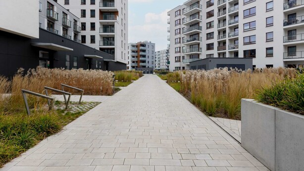 A pathway leading to modern apartment buildings with balconies, surrounded by landscaped areas with tall grasses. - Stylish Studio | Parking, close to Młociny Metro (Warszawa)
