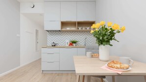 A modern kitchen with white cabinets, a wooden countertop, and a vase of yellow flowers on a table. - Stylish Studio | Parking, close to Młociny Metro (Warszawa)