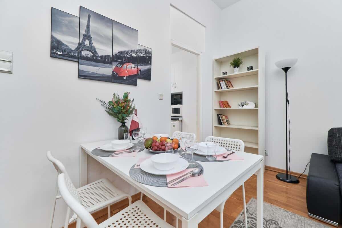 Ein Essbereich mit einem weißen Tisch, gedeckt für vier Personen, einem Bücherregal und einer Stehlampe.