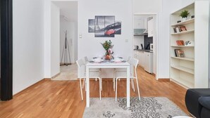 A modern living space with a dining area, kitchen, and a bookshelf.