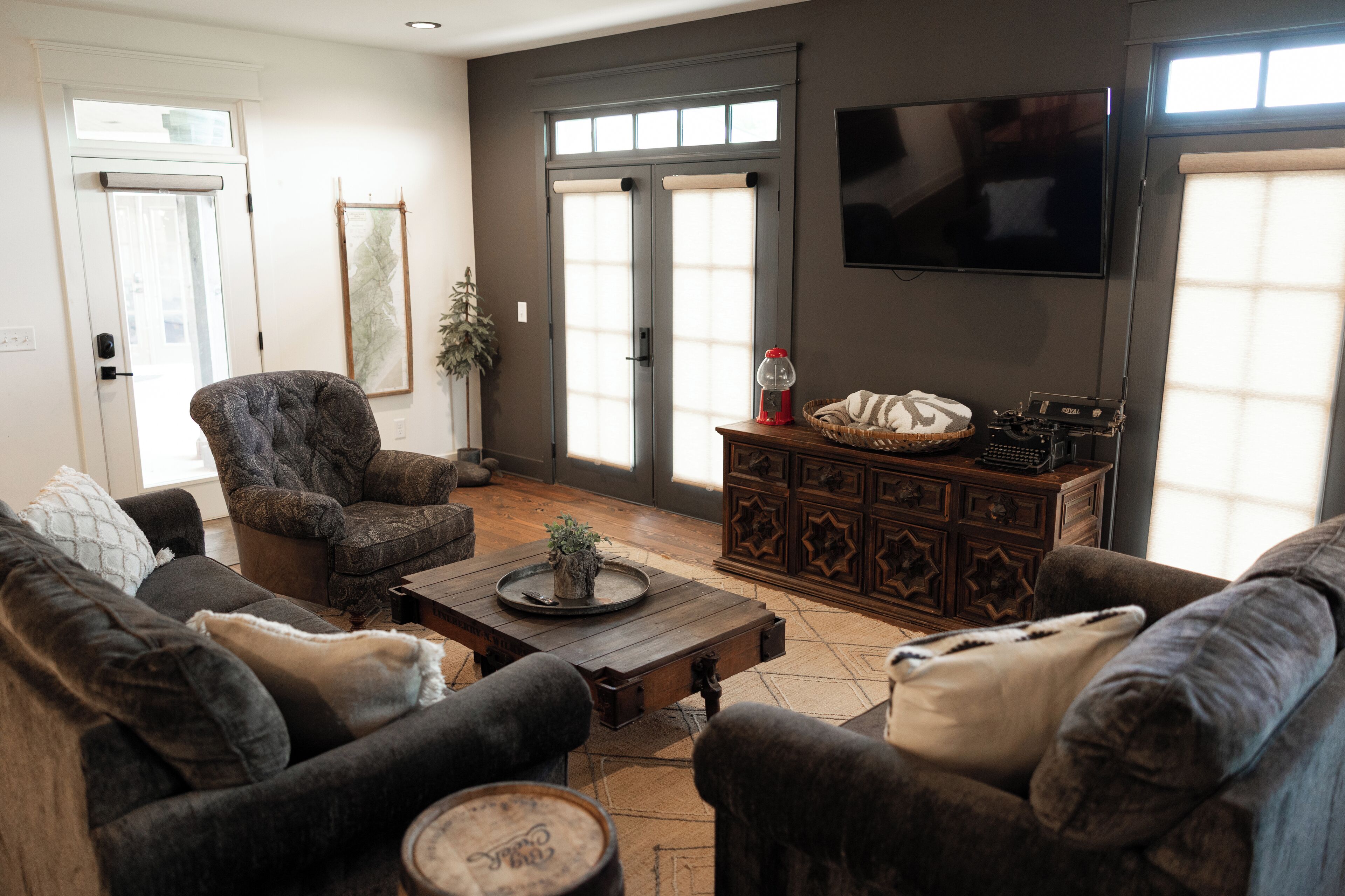 A living room with dark-toned furniture, a wooden coffee table, and a television mounted on the wall.