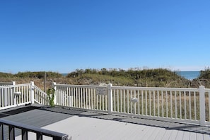 A wooden deck with a white railing, overlooking a beach and dunes. - Ocean Towers 101 (North Myrtle Beach)