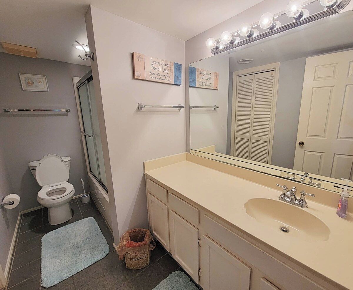 A bathroom with a toilet, sink, mirror, and towel rack.