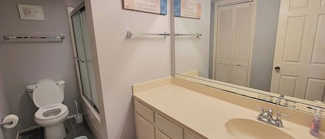 Un bagno con il water, un lavandino, uno specchio e un porta asciugamani.