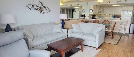 A living room with a sofa, a coffee table, and a dining area with chairs.