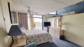 Une chambre d’hôtel avec un lit, une télévision, une commode et un balcon.