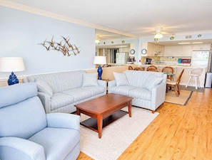 A living room with two sofas, a coffee table, and a dining area with chairs.
