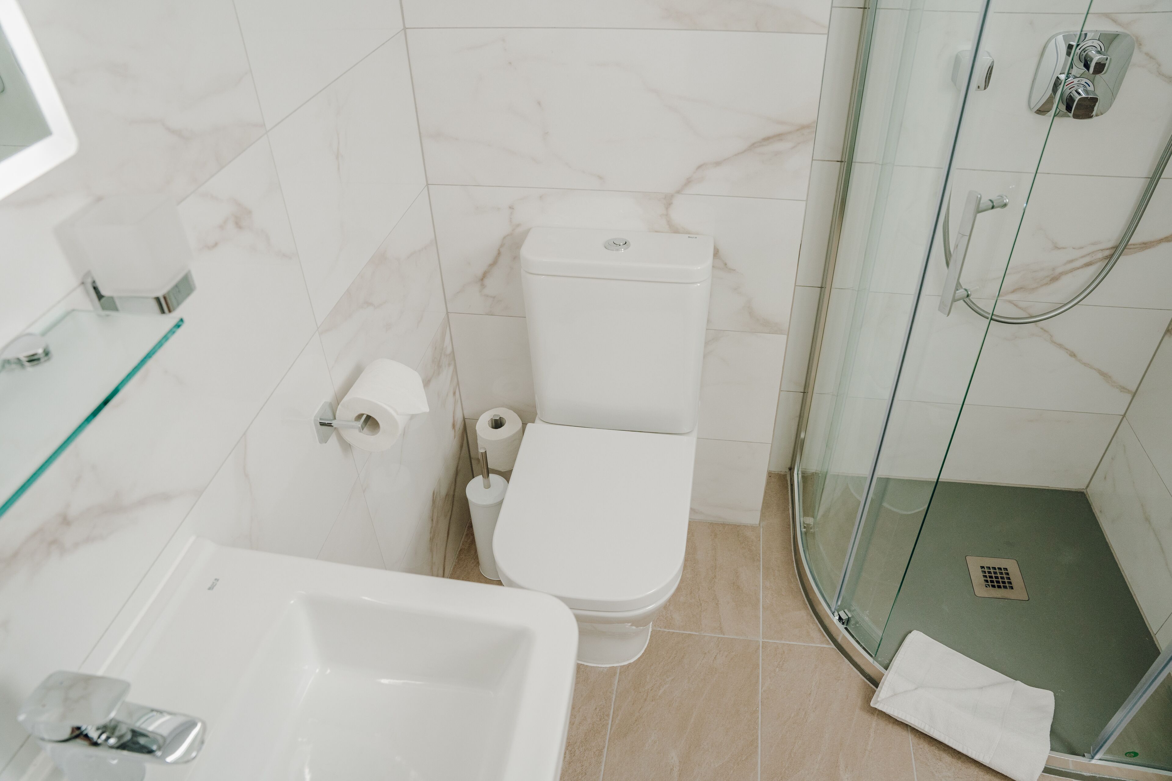 Un baño con inodoro, bidé y ducha con mampara de cristal.