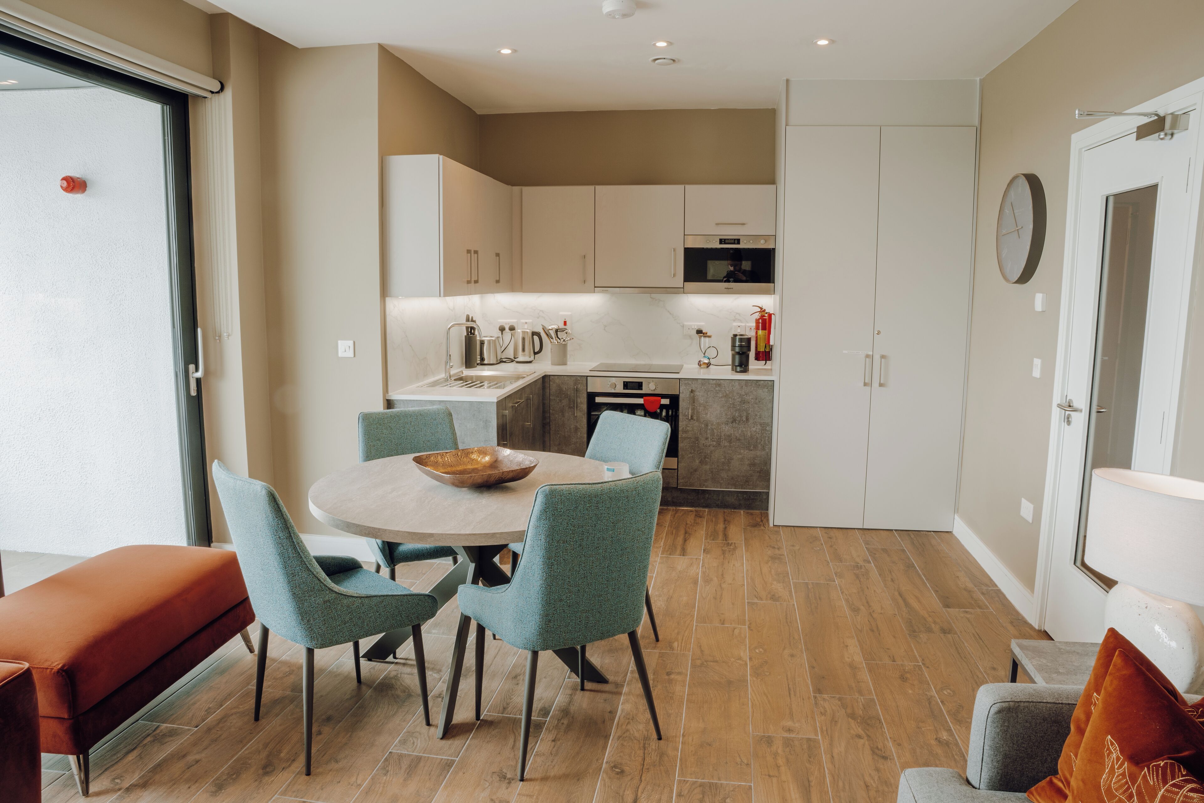 A modern kitchen with white cabinets, a central island with seating, and a dining area with a round table and chairs.