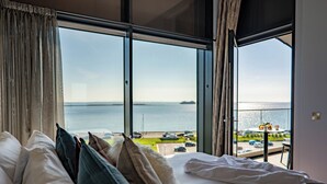 A hotel room with a large window offering a view of the sea and a distant island. - Shoreline Apartments (Galway)