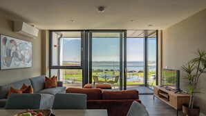 A modern living room with a large sliding glass door leading to a balcony with a view of the sea. - Shoreline Apartments (Galway)