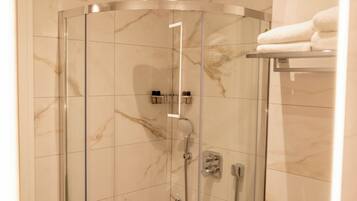 Een douche met glazen wand, een handdouche, een wandmengkraan en bedieningspaneel.