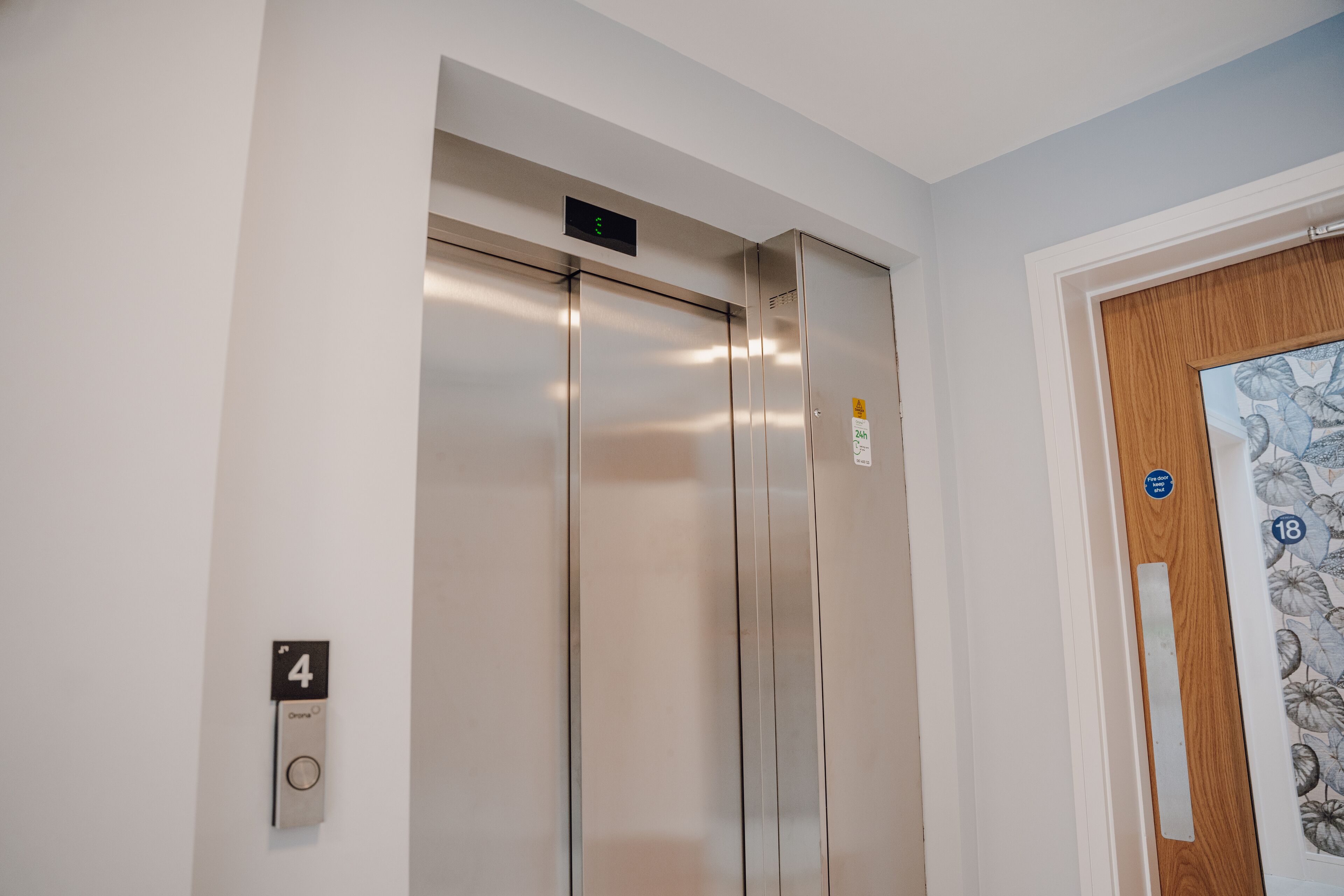 An elevator with a digital display, a door with a number 4 sign, and a door with a floral pattern.