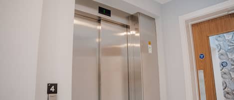 An elevator with a digital display, a door with a number 4 sign, and a door with a floral pattern.