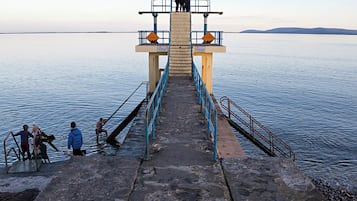 A pier leading to a small platform with railings and a sign.