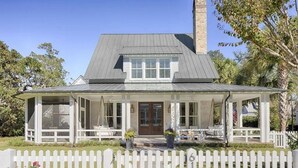 Een huis met twee verdiepingen, een veranda, schoorsteen en een witte picket-heg.