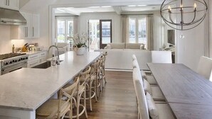 Een ruime keuken met een groot eiland, houten stoelen en een eettafel.