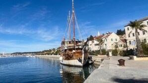A historic sailing ship docked at a harbor with buildings and a clear sky in the background.