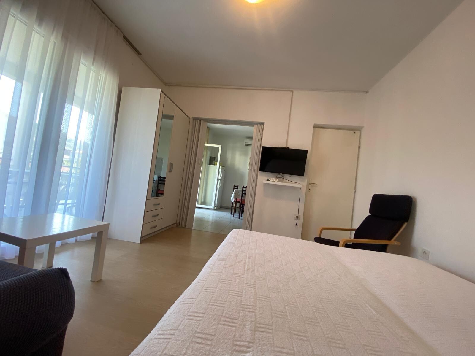 Een hotelkamer met een bed, een aan de muur bevestigde televisie, een stoel en een bureau.