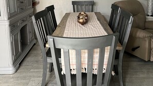 A dining room with a wooden table, six chairs, a chandelier, and a cabinet. - Sugar Beach-C16 Unique in the best way. Just updated be first to enjoy upgrades. (Panama City)