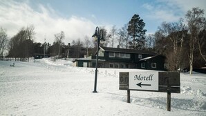 Un paysage enneigé avec un panneau indiquant la direction d’un motel.
