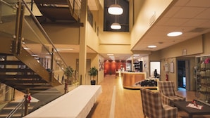 Un hall d’entrée spacieux comprenant un comptoir d’accueil, un espace détente et un présentoir à chaussures.