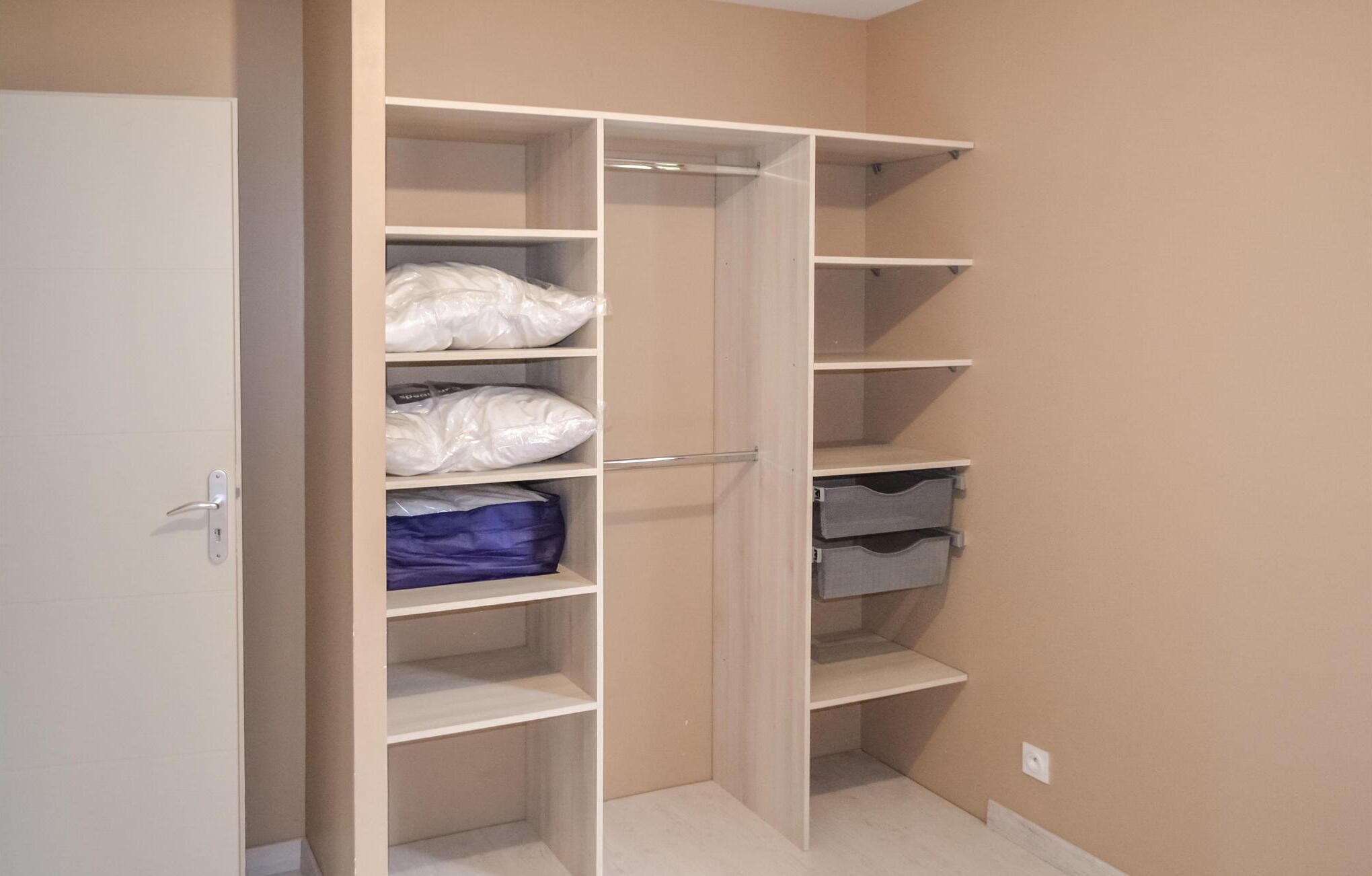 Un vestidor amplio con estantes y cajones múltiples, algunos con bolsos.