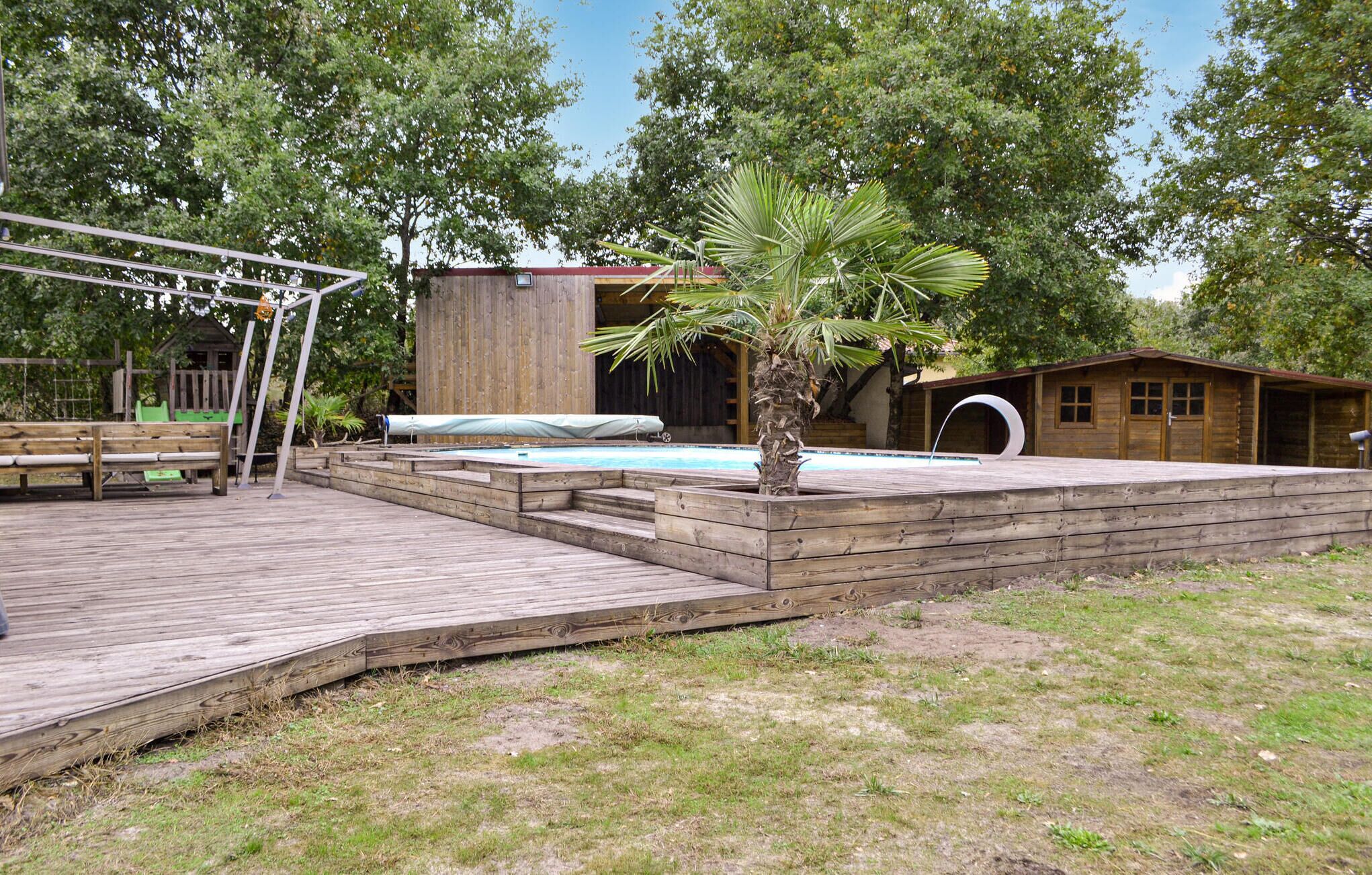 A wooden deck with a pool, a palm tree, and a wooden building with a door and windows.