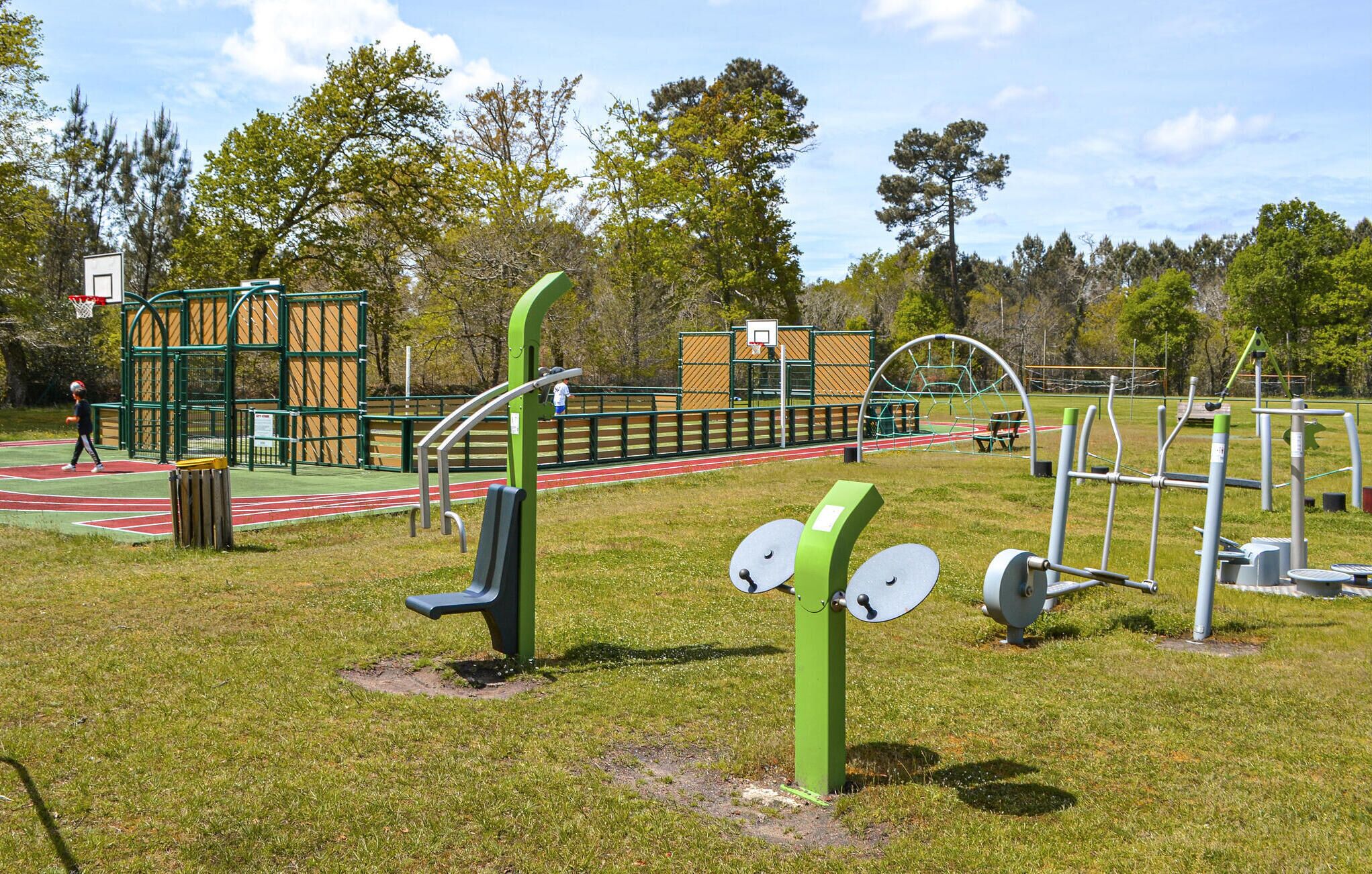 An outdoor gym with exercise equipment, a basketball court, and a running track.