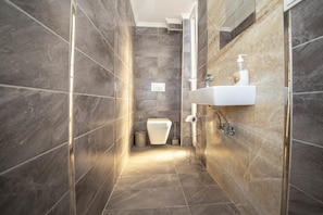A modern bathroom with dark marble tiles, a white sink, and a toilet. - Villa With Sea View and Terrace in Milas Bodrum (Milas)