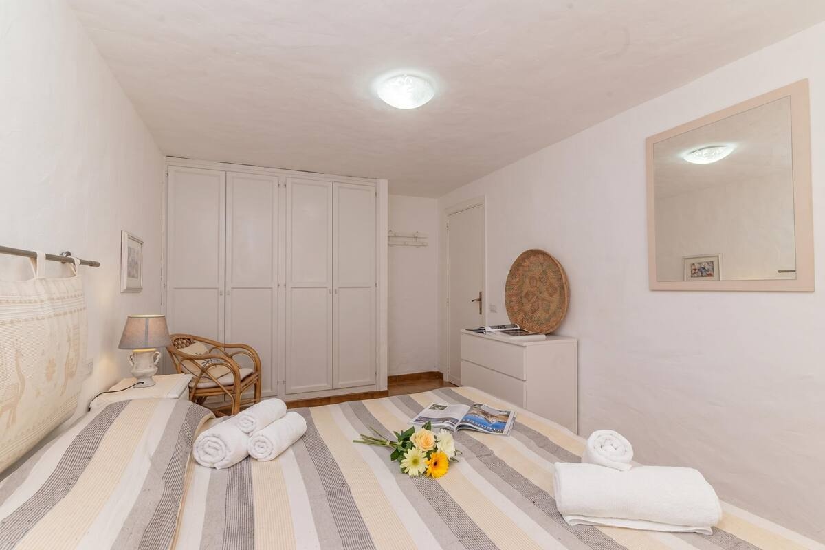 Ein Schlafzimmer mit einem Bett, einem Sessel, einem Schminktisch und einer Tür.