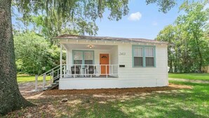 A small, single-story house with a porch, a front door, and a mailbox. - Orange Door Bungalow - Central, Cozy, 3BR (Jacksonville)
