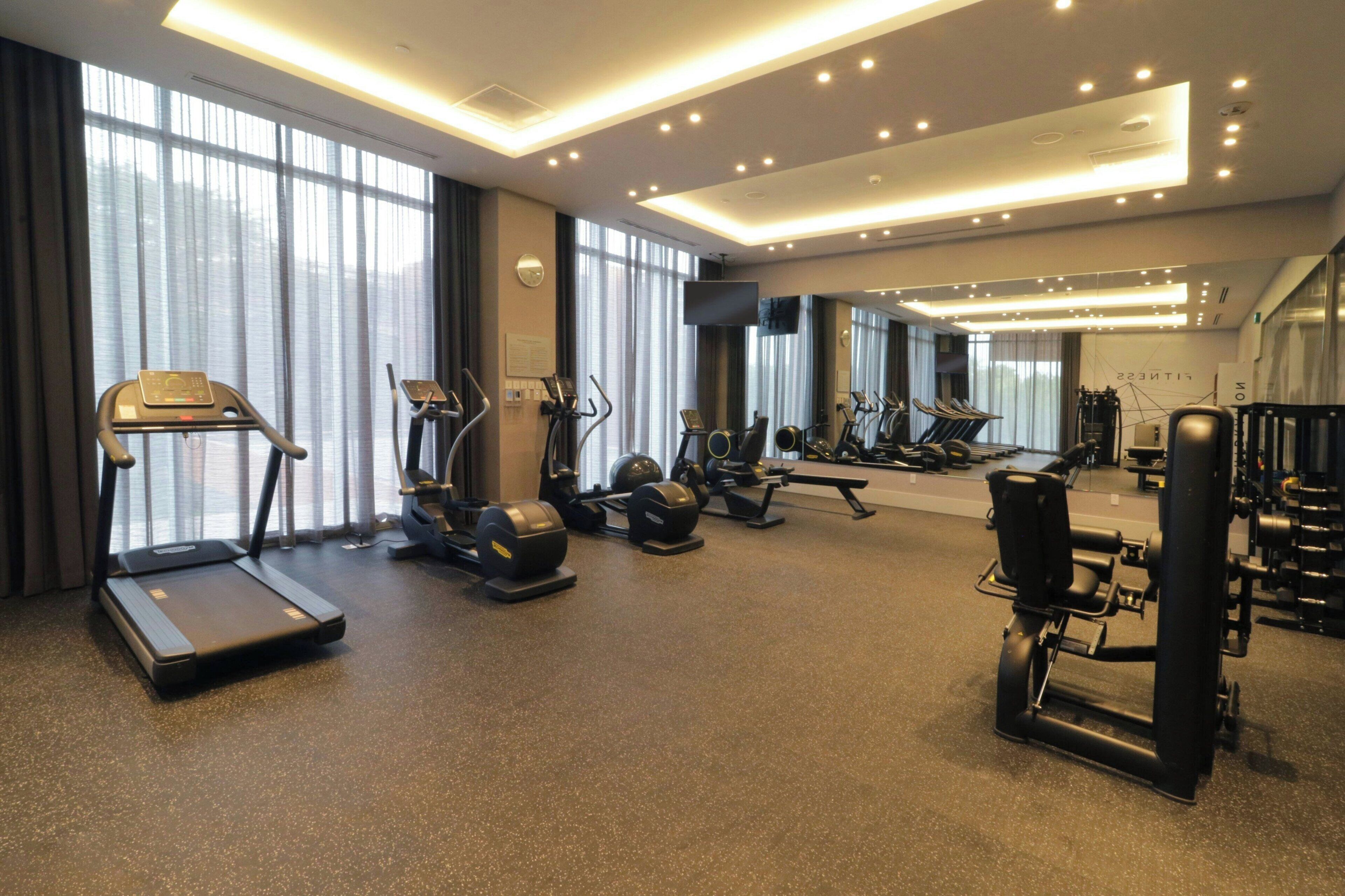 Une salle de sport équipée de tapis de course, de vélos elliptiques et d’appareils de musculation.
