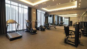 Une salle de sport équipée de tapis de course, de vélos elliptiques et d’appareils de musculation.