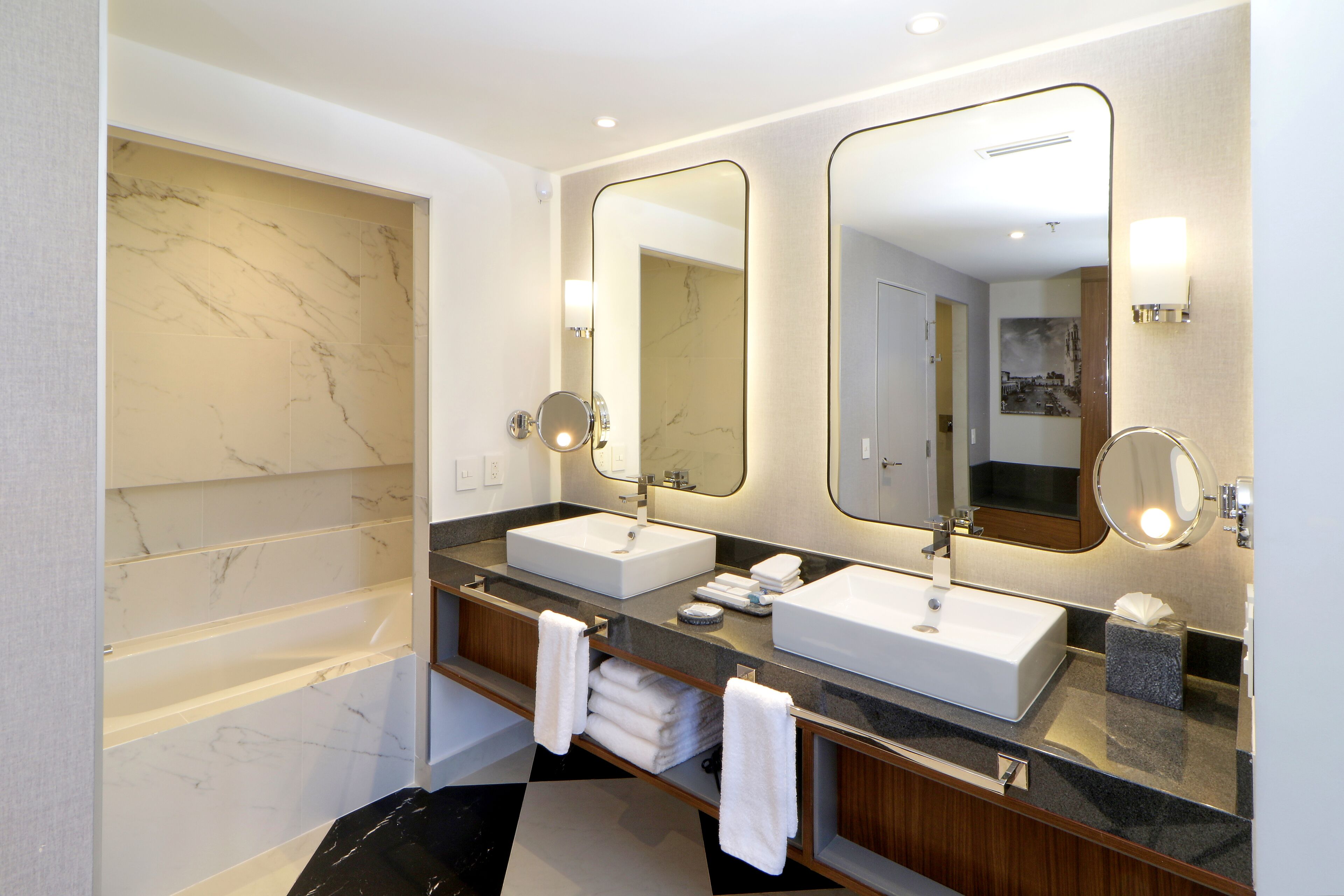 Un baño moderno con dos lavamanos, un espejo grande y una bañera.