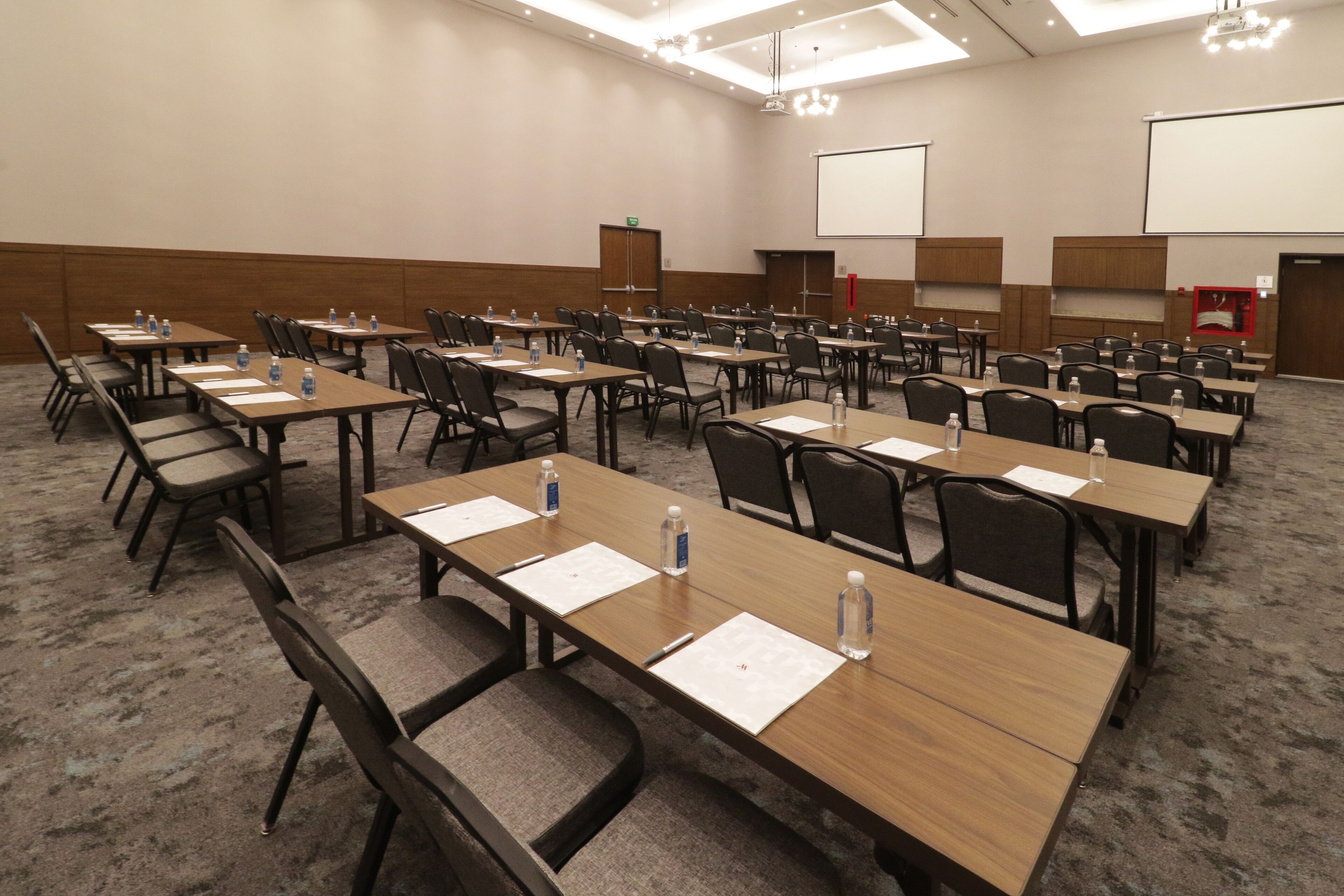 Une salle de conférence dotée de plusieurs tables et de chaises, ainsi que de bouteilles d’eau et de blocs-notes.