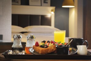 A breakfast tray with toast, fruit, a glass of orange juice, and a mug, set on a table in a hotel room. - Marriott Culiacan Hotel (Culiacán)