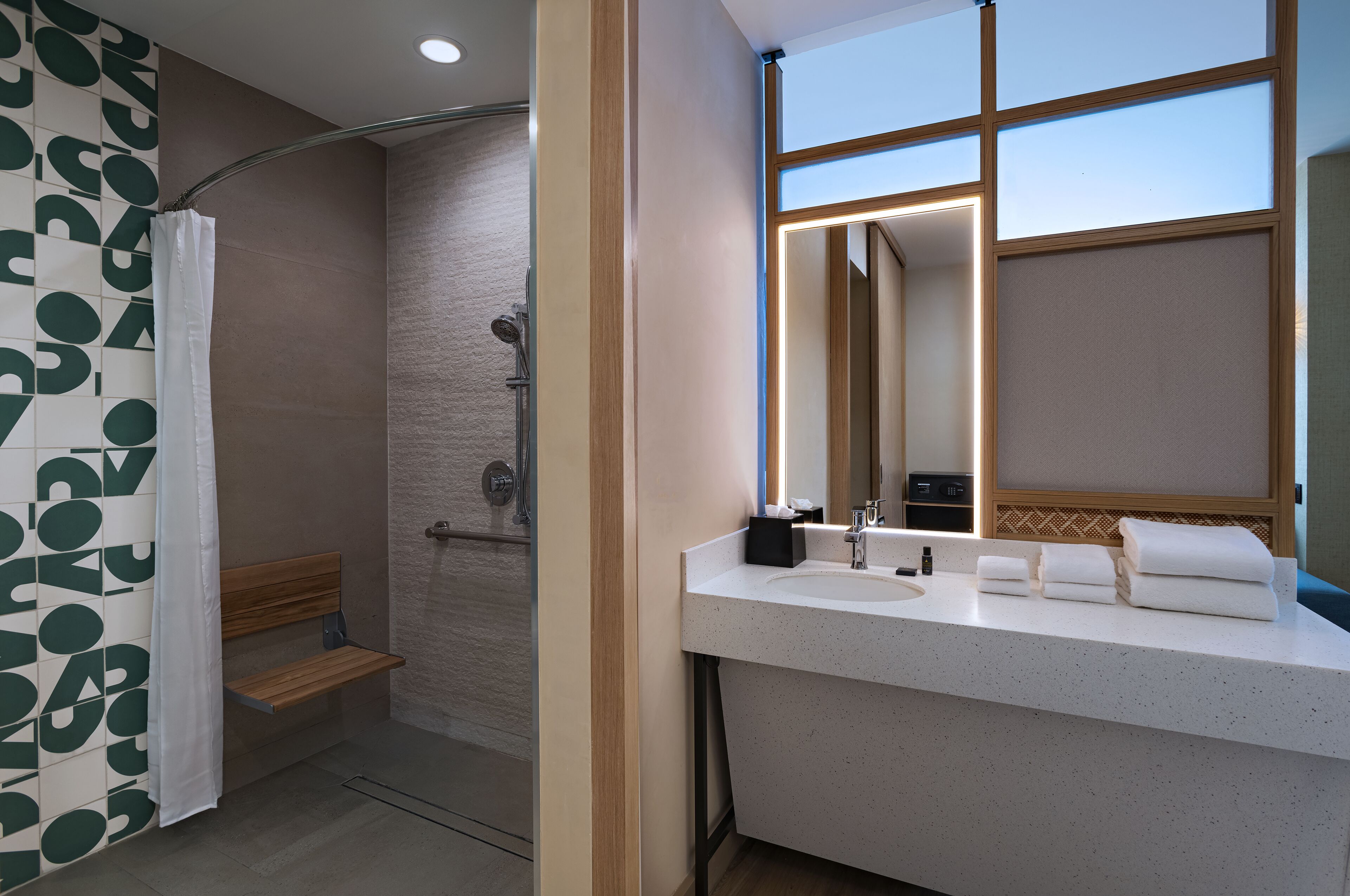 A modern bathroom with a shower, a vanity with a mirror, and a towel rack.