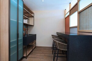 A modern kitchen with a dark countertop, wooden cabinets, and a bar area with wicker chairs.