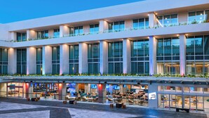 Un hotel moderno con un amplio espacio de estar al aire libre, varios pisos y grandes ventanales.