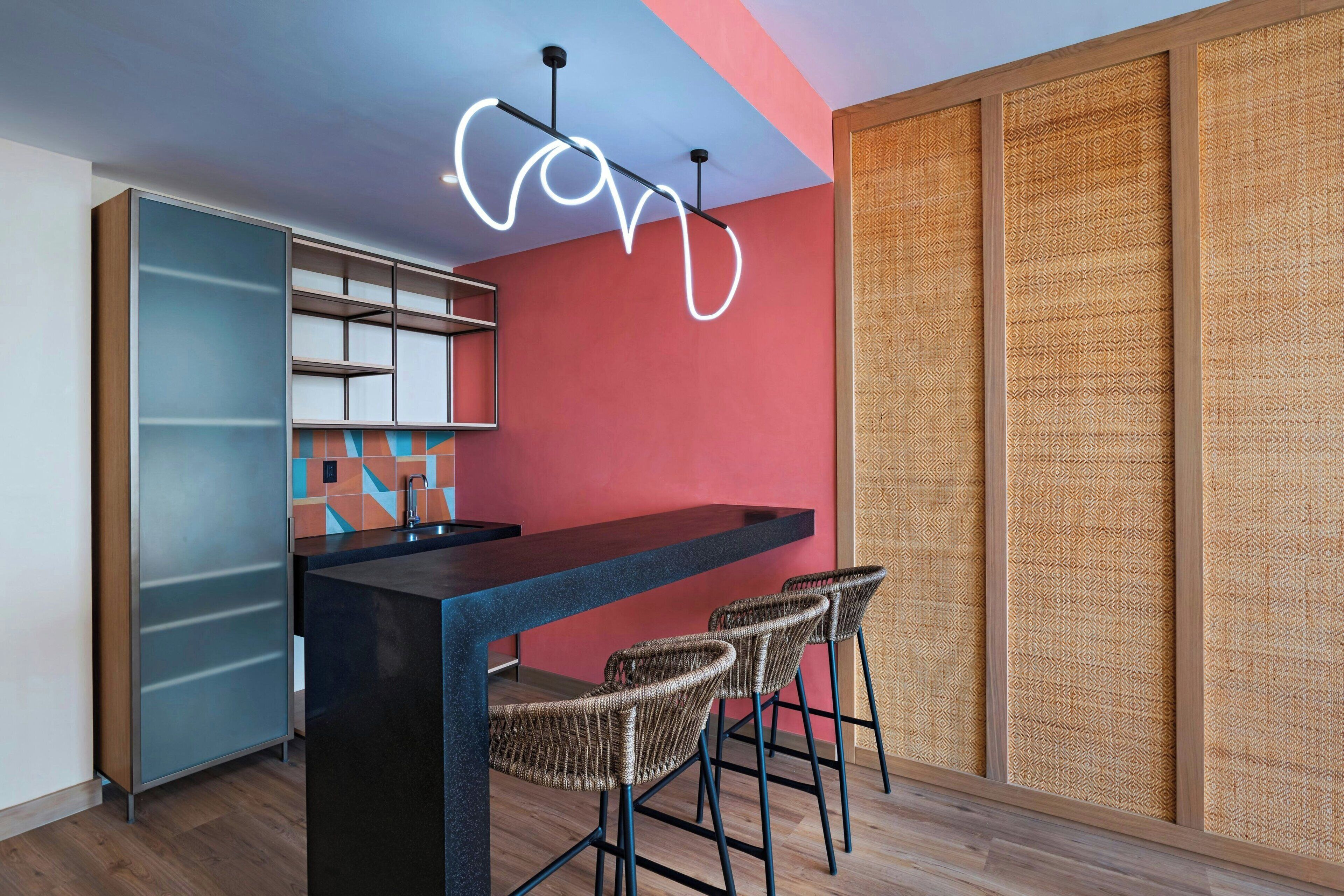 Una cocina moderna con barra, taburetes y luz de neón.