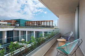 A modern balcony with glass railings, two chairs, and a small table.