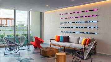 A modern lounge with a sofa, colorful cushions, and unique chairs.