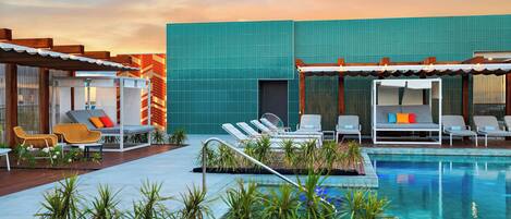 A pool area with lounge chairs and a view of a modern building.