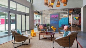 A spacious lobby with wicker chairs, a round coffee table, and a large window. - Aloft by Marriott Playa del Carmen (Playa del Carmen)