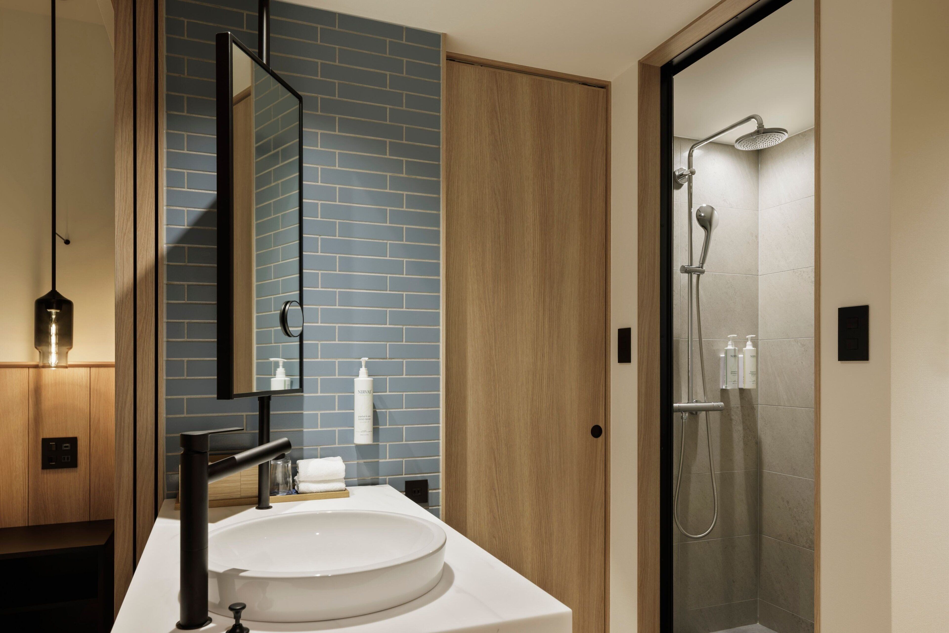 Un baño moderno con un espejo grande, un lavabo redondo y zona de ducha.
