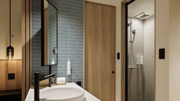 Un baño moderno con un espejo grande, un lavabo redondo y zona de ducha.