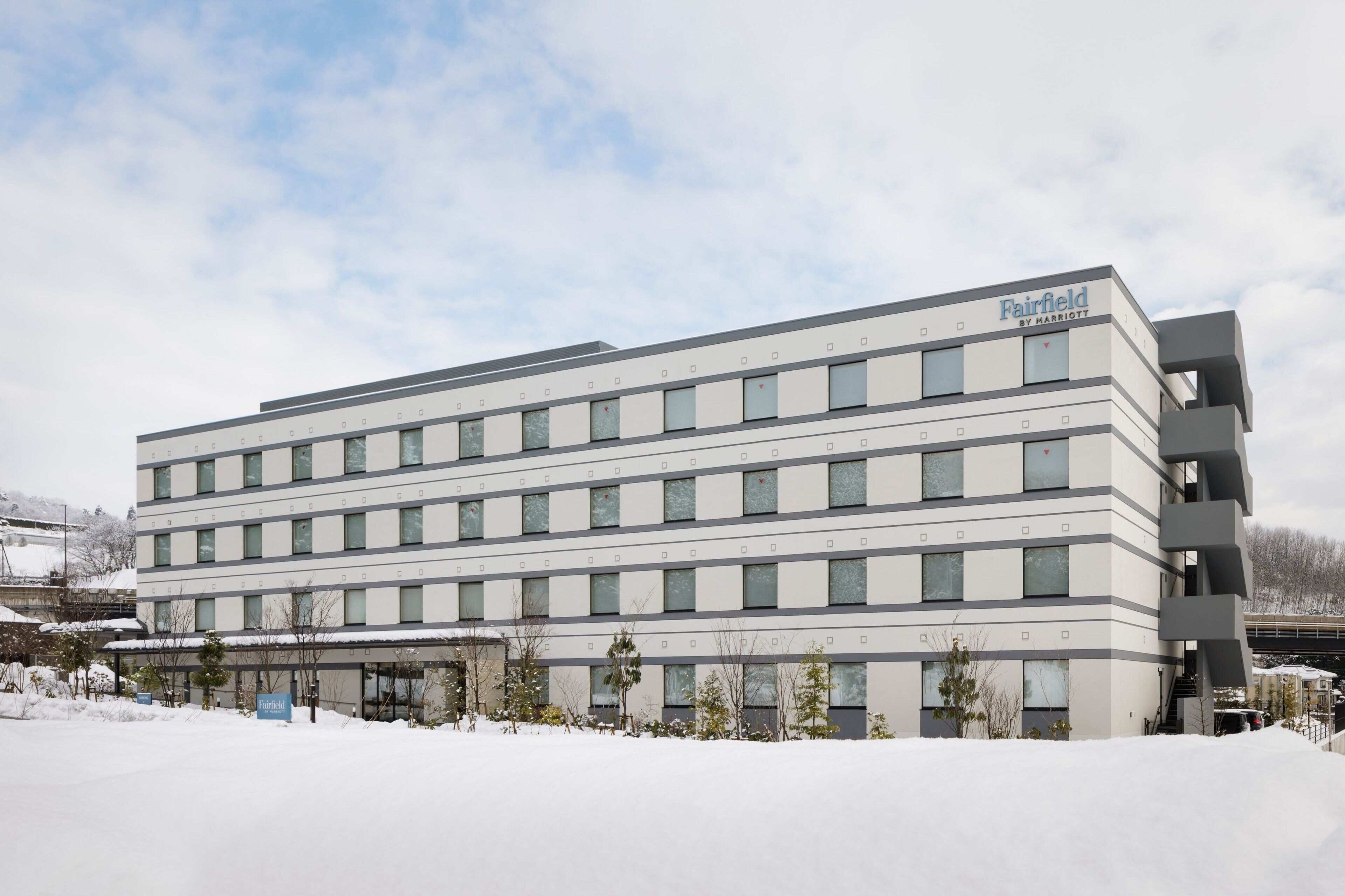 Un hôtel moderne, avec une façade sobre, de nombreuses fenêtres et une enseigne indiquant qu’il fait partie de la chaîne Fairfield by Marriott.