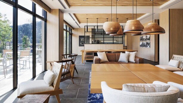 Un interior moderno con una gran mesa de comedor de madera, asientos cómodos y amplias ventanas con vistas al exterior.